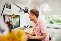 Man sitter vid ett skrivbord på sitt hemmakontor har ett digitalt möte