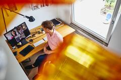 en man sitter vid sitt hemmakontor, sett ovanifrån, pratar med sina kollegor i ett onlinemöte