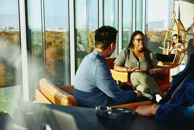 Två personer har en konversation sittandes i en lounge miljö