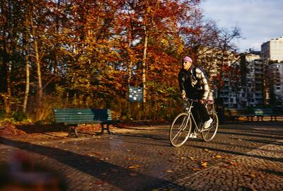 en ung kille cyklandes, på väg till intervju, höstträd och byggnader i bakgrunden