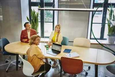 Group of people sitting at a oval table, having a meeting