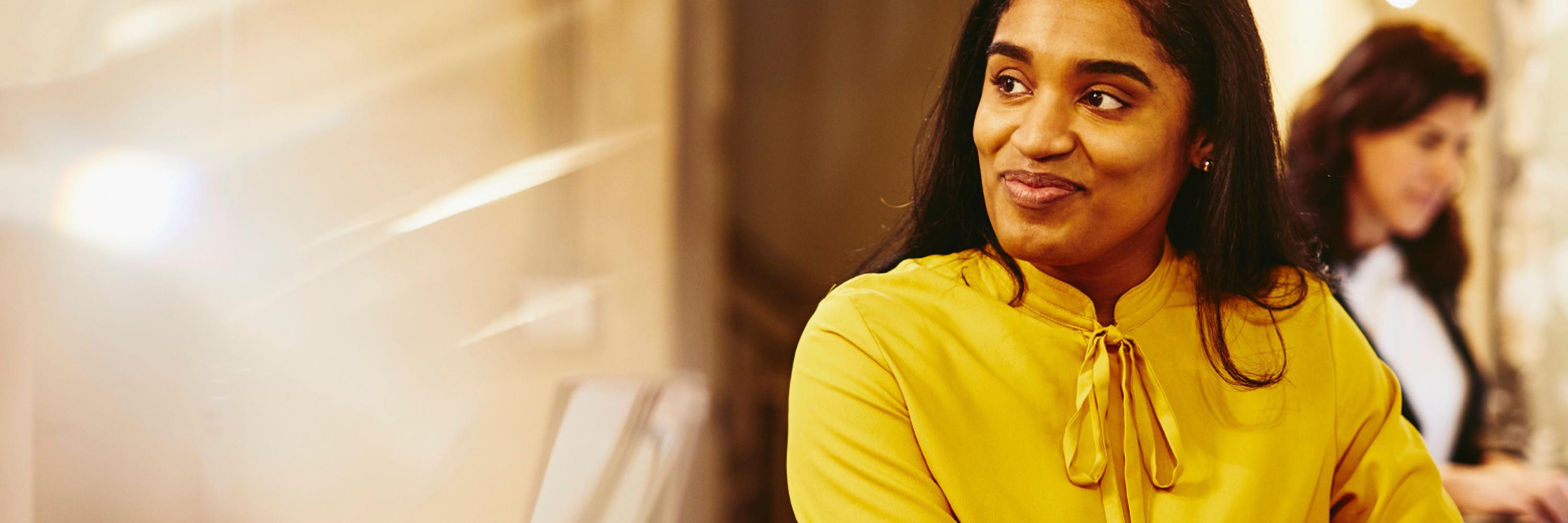 a woman in a yellow blouse, in close-up, looks sideways to the right