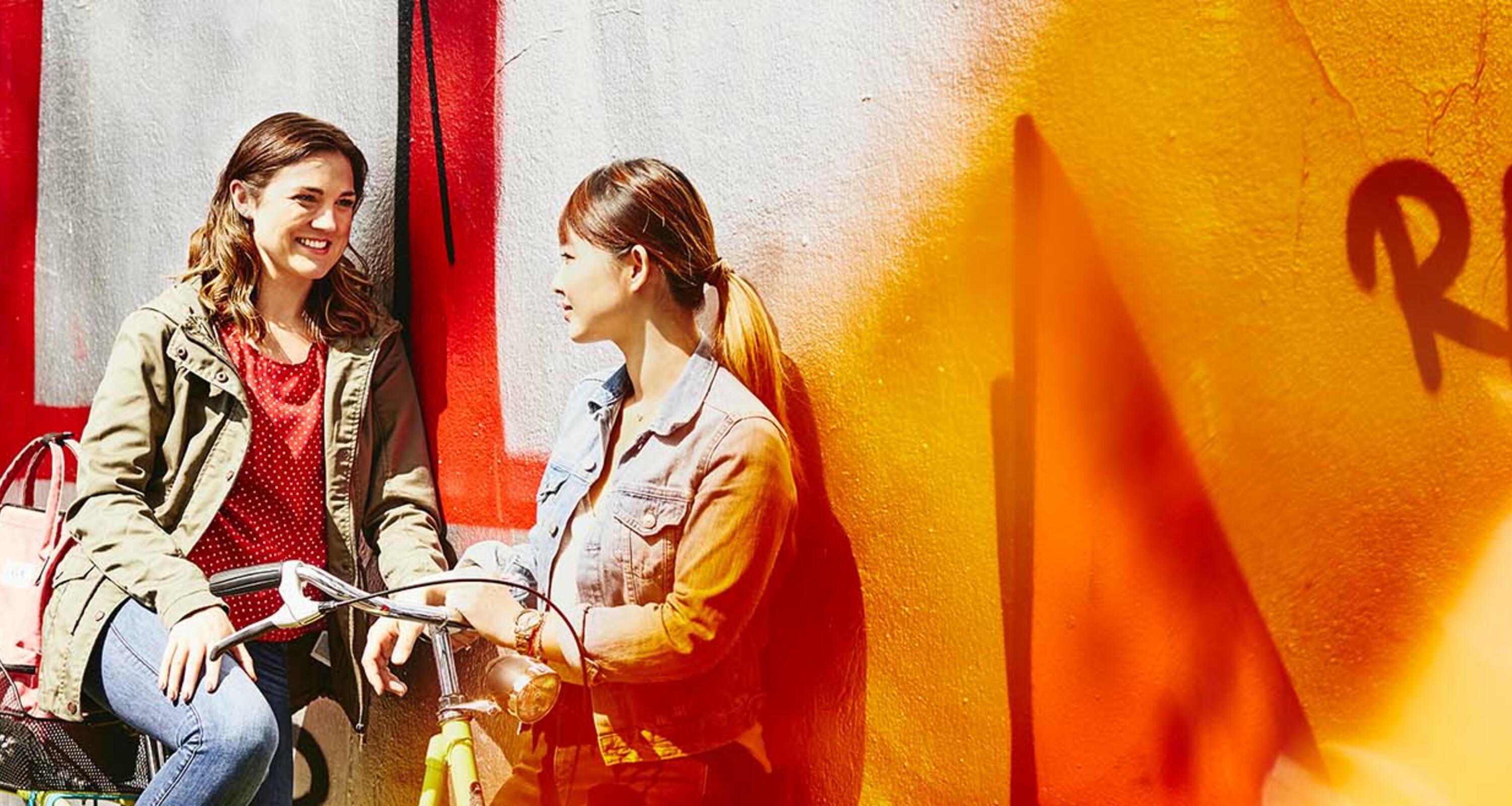 two students is sitting outside on a bench talking