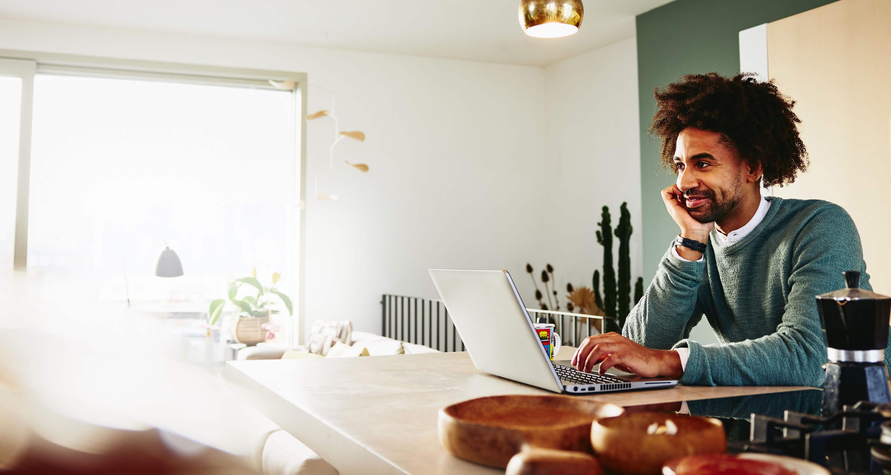 man leaning against the computer top while working  on the laptop