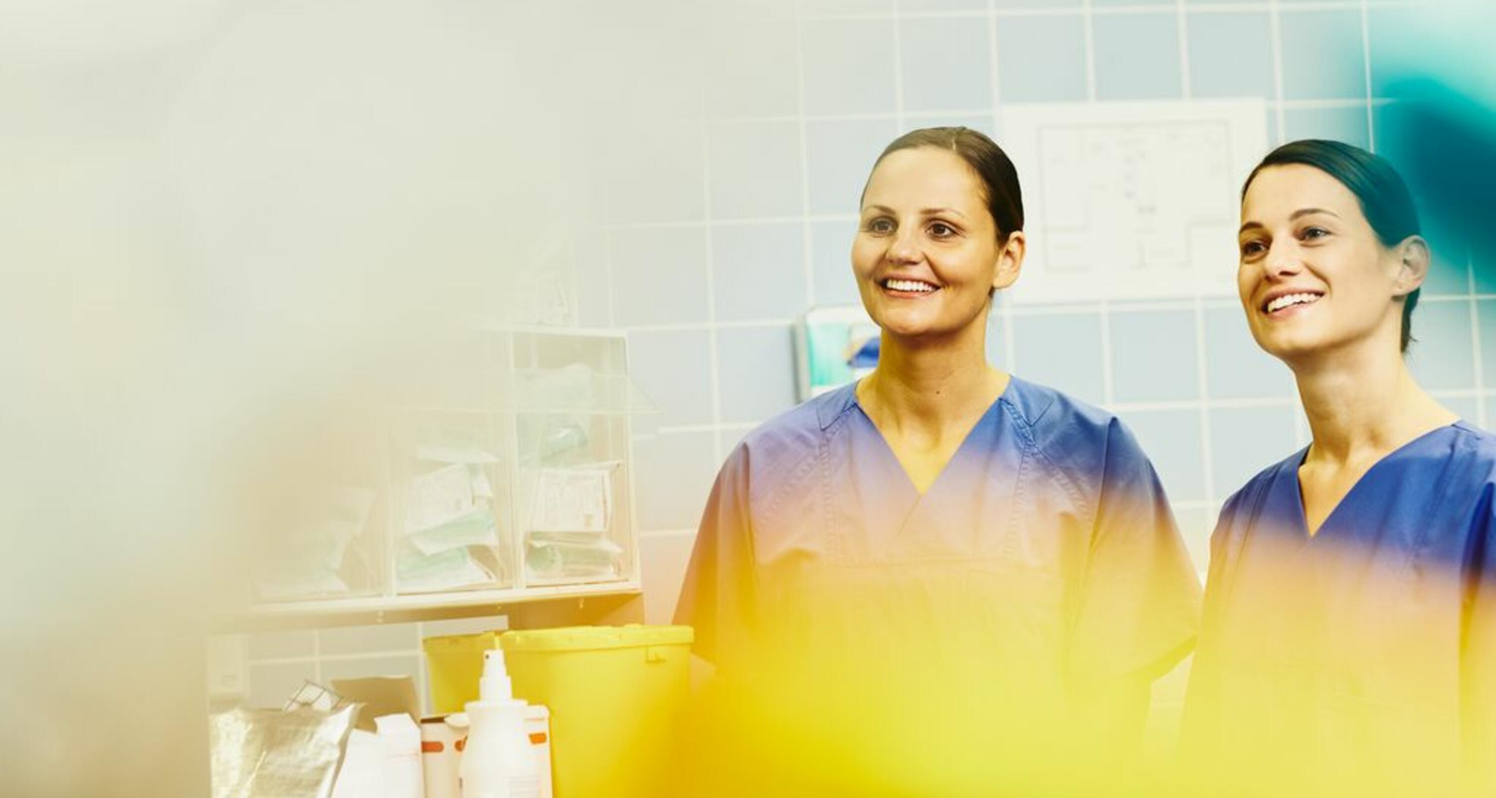 två leende kvinnliga sjuksköterskor i blåa arbetsrockar