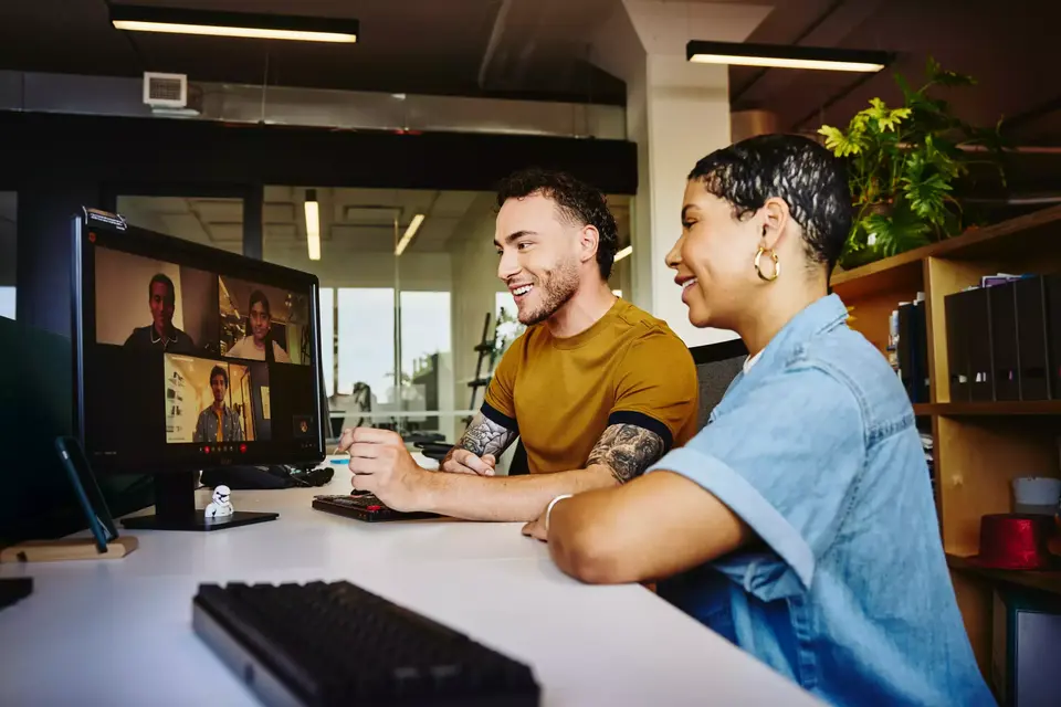 Male and female sitting behind a computer in a video meeting