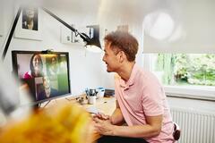 Man sitter vid ett skrivbord på sitt hemmakontor har ett digitalt möte