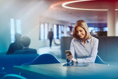 Business woman with tablet looking at her phone. Primary color: blue.
