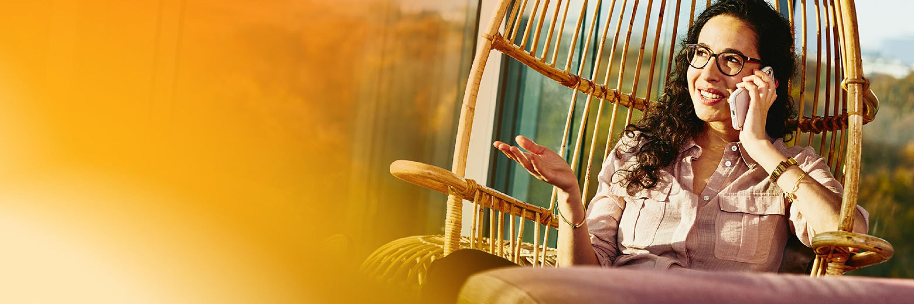 a women sitting in a chair by the window, talking in here mobile
