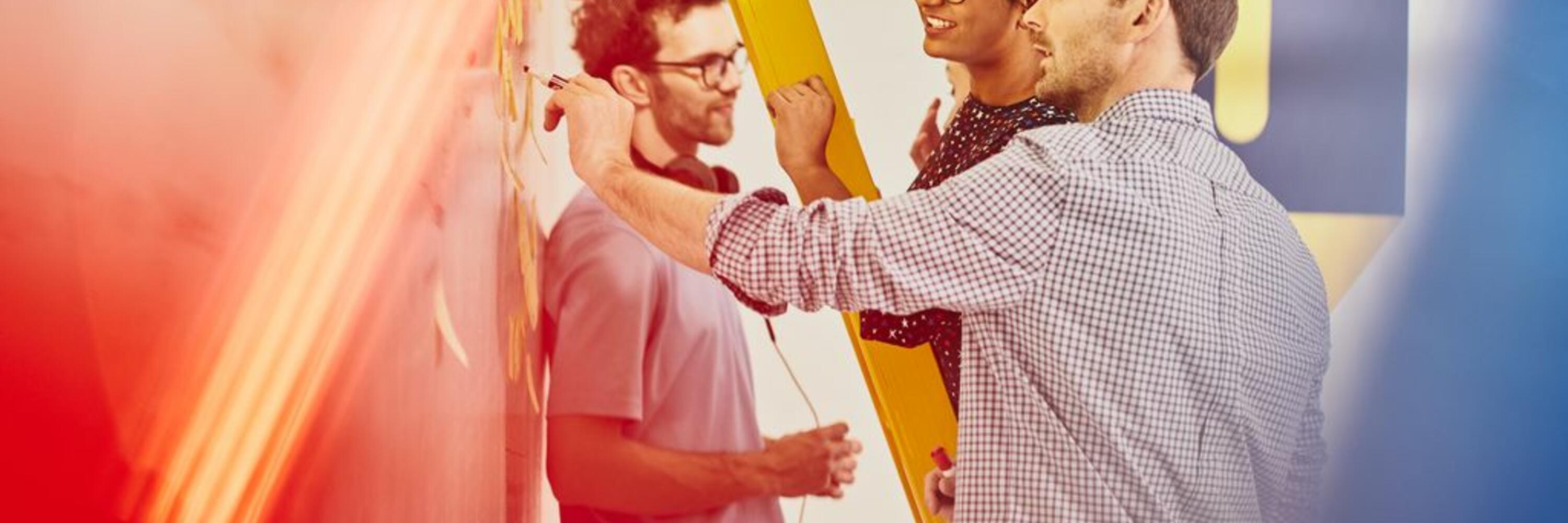 4 colleagues standing at a whiteboard, working on a project
